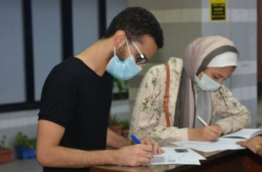 Koronavirüs aşısı olmadan önce Coronavirus aşısı belgelerini imzalayan öğrenciler, Mısır üniversiteleri aşı öğrencileri, yeni öğretim yılı öncesinde çalışanlar, aşı olmadan önce koronavirüs aşısı onayını okuyup imzalıyorlar.