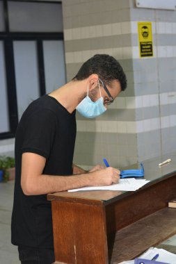 Koronavirüs aşısı olmadan önce Coronavirus aşısı belgelerini imzalayan öğrenciler, Mısır üniversiteleri aşı öğrencileri, yeni öğretim yılı öncesinde çalışanlar, aşı olmadan önce koronavirüs aşısı onayını okuyup imzalıyorlar.