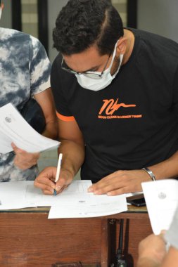 Koronavirüs aşısı olmadan önce Coronavirus aşısı belgelerini imzalayan öğrenciler, Mısır üniversiteleri aşı öğrencileri, yeni öğretim yılı öncesinde çalışanlar, aşı olmadan önce koronavirüs aşısı onayını okuyup imzalıyorlar.