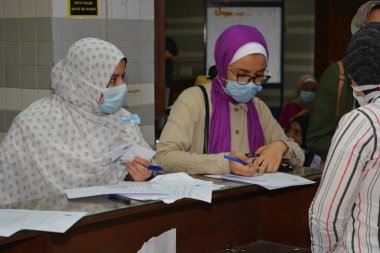 Koronavirüs aşısı olmadan önce Coronavirus aşısı belgelerini imzalayan öğrenciler, Mısır üniversiteleri aşı öğrencileri, yeni öğretim yılı öncesinde çalışanlar, aşı olmadan önce koronavirüs aşısı onayını okuyup imzalıyorlar.