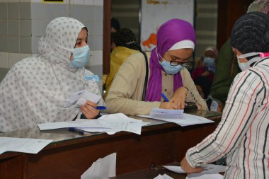 Koronavirüs aşısı olmadan önce Coronavirus aşısı belgelerini imzalayan öğrenciler, Mısır üniversiteleri aşı öğrencileri, yeni öğretim yılı öncesinde çalışanlar, aşı olmadan önce koronavirüs aşısı onayını okuyup imzalıyorlar.