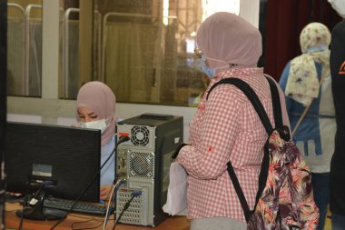 Bir bilişim personeli, Mısır vatandaşlarını salgın hastalığa karşı aşıladığı için covid-19 aşısı ve koronavirüs aşısı yaptıracak çevrimiçi kayıtlı insanları kontrol ediyor.