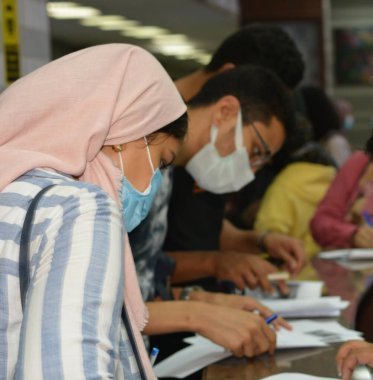 Koronavirüs aşısı olmadan önce Coronavirus aşısı belgelerini imzalayan öğrenciler, Mısır üniversiteleri aşı öğrencileri, yeni öğretim yılı öncesinde çalışanlar, aşı olmadan önce koronavirüs aşısı onayını okuyup imzalıyorlar.
