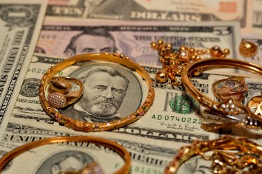 Bir dizi altın aksesuar yüzük, zincir ve bilezik Amerikan doları üzerine para, altın değer konsepti, mücevher alıcısı, rehin dükkanı, değerli metalleri alıp satma konsepti.