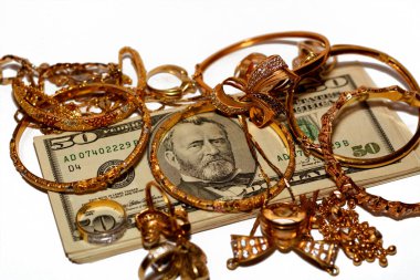 Bir yığın Amerikan doları para banknotları bir dizi altın aksesuar yüzük, kolye zinciri ve bilezikler beyaz arka planda izole edilmiş, altın değer, sat ve satın al konsepti, seçici odaklanma