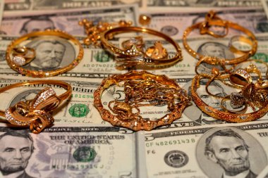 Bir dizi altın aksesuar yüzük, zincir ve bilezik Amerikan doları üzerine para, altın değer konsepti, mücevher alıcısı, rehin dükkanı, değerli metalleri alıp satma konsepti.