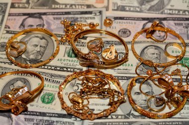 Bir dizi altın aksesuar yüzük, zincir ve bilezik Amerikan doları üzerine para, altın değer konsepti, mücevher alıcısı, rehin dükkanı, değerli metalleri alıp satma konsepti.