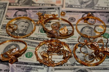 Bir dizi altın aksesuar yüzük, zincir ve bilezik Amerikan doları üzerine para, altın değer konsepti, mücevher alıcısı, rehin dükkanı, değerli metalleri alıp satma konsepti.