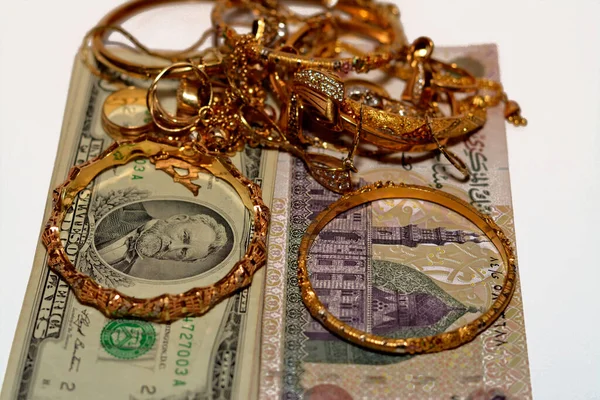 Bir yığın Mısır sterlini ve Amerikan doları para banknotları bir dizi altın aksesuar yüzük, kolye ve bilezikler beyaz arka planda izole edilmiş, altın değer, satmak ve konsept satın almak