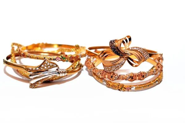 İzole edilmiş beyaz bir arka planda mücevher, bir dizi altın bilezik 21 karat tasarım altın mücevherler, değerli metal takılar, seçici bir odak noktası olan bileklik.