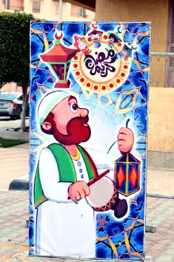 Kahire, Mısır, 23 Mart 2022: Sokakta bir Ramazan süsü, şafaktan önce oruç ve çevirilerinden önce yemek yemek için uyanan bir kişi.)