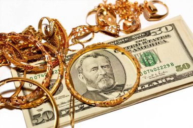 Bir yığın Amerikan doları para banknotları bir dizi altın aksesuar yüzük, kolye zinciri ve bilezikler beyaz arka planda izole edilmiş, altın değer, sat ve satın al konsepti, seçici odaklanma