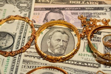 Bir dizi altın aksesuar yüzük, zincir ve bilezik Amerikan doları üzerine para, altın değer konsepti, mücevher alıcısı, rehin dükkanı, değerli metalleri alıp satma konsepti.