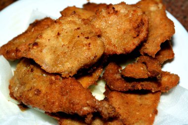 Kızarmış tavuk göğsü, yağda kızartılmış, aromalı altın renginde, beyaz bir tabakta servis edilmiş, kızarmış tavuk fileto göğsü.