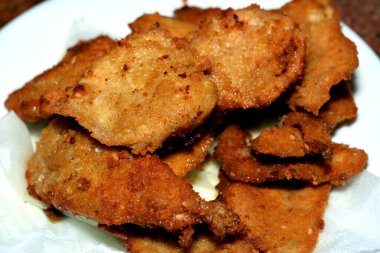 Kızarmış tavuk göğsü, yağda kızartılmış, aromalı altın renginde, beyaz bir tabakta servis edilmiş, kızarmış tavuk fileto göğsü.