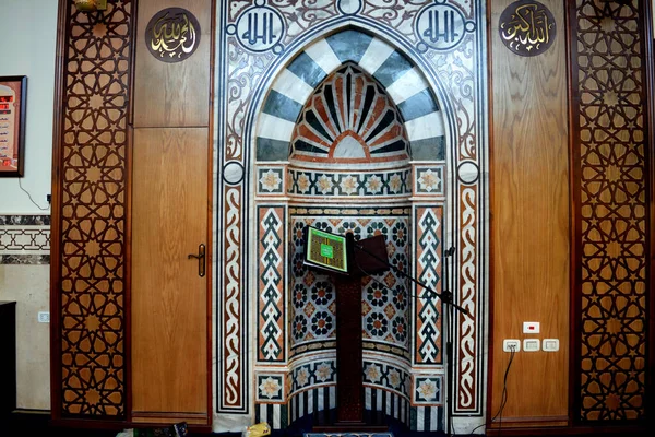 清真寺内部有伊斯兰装饰风格的清真寺 清真寺Mihrab或小木屋 古兰经 的木制台架和麦克风 阿拉伯文字的翻译 真主是最伟大的 有选择的焦点 — 图库照片
