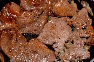 Biftek parçaları ızgarada yağ, soğan dilimleri, ızgarada tuz ve karabiber, seçici odaklı biftek pişirme, et tarifi Mısır usulü yapılır.