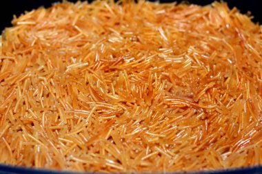 Pişirme kabında su ve şekerle pişirilmiş tereyağlı tatlı Mısırlı vermicelli. Geç öğle ve erken akşam yemeğinde geleneksel Mısır tatlıları, Mısır tarifinin seçici odak noktası