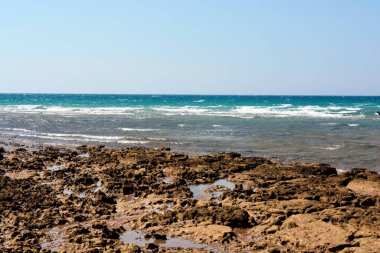 Yazın gün ışığında Mısır 'ın güney Sina' sındaki kumlu ve kayalık kumsalda deniz dalgalı insanların olmadığı doğal panoramik boş kıyılar kumsaldaki kayalara ve kumlara vurur.