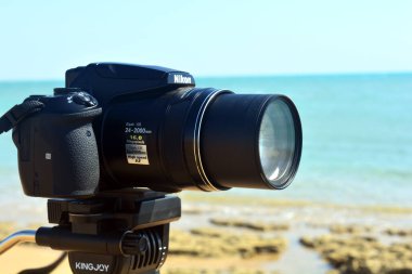 Sinai, Mısır, 23 Ağustos 2018: Nikon dijital kamerası bir tripodun üzerinde kızıl denizin önündeki Güney Sina sahilinde doğal bir sahneyi çekiyor ve kaydediyor, Nikon coolpix P900 'ün seçici odak noktası