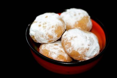 Geleneksel Arap kurabiyeleri El-Fitr bayramını kutlamak için, Mısır kahvesi pudra şekerle kaplanmış, ceviz ve fındık ile doldurulmuş ve siyah bir tabakta izole edilmiş kırmızı tabakta.