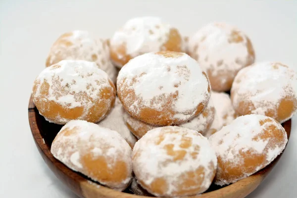 Geleneksel Arap kurabiyeleri El-Fitr bayramını kutlamak için, Mısır kahvesi pudra şekerle kaplanmış, içi ceviz dolu ve beyaz üzerine izole edilmiş tahta bir tabakta.