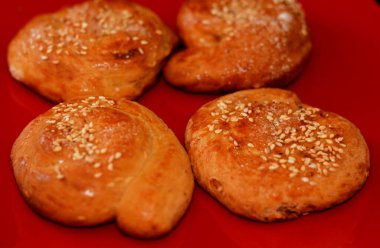 Siyah zemin üzerine izole edilmiş seramik kırmızı bir tabakta susam ve şekerle kaplı Arap Mısırlı yuvarlak kurabiyeler, Kurban Bayramı tatlısı ve Ramazan tatlıları, seçici bir odak noktası.