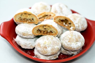 El-Fitr bayramını kutlamak için kırmızı tabak geleneksel Arap kurabiyeleri, pudra şekeri, fındık ve fındık dolması ve beyaz üzerine izole edilmiş Malban kahvesi.