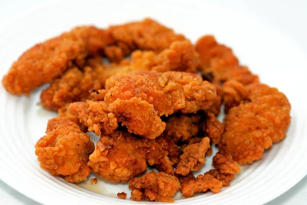 A plate of chicken strips fired in deep oil isolated on white background, selective focus of chicken fingers, tenders, fillet or goujons are white chicken meat from either sides of breast bone