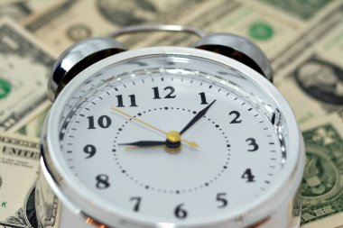 Bulanık Amerikan para banknot para banknotlarının arka planında bir çalar saat, dakika ve saniye ölçeğinde bir zamanlayıcı ile Amerikan doları arka planı, zaman para kavramı, seçici odaklanma