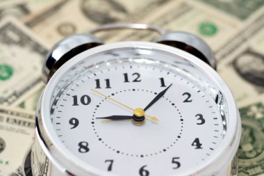 Bulanık Amerikan para banknot para banknotlarının arka planında bir çalar saat, dakika ve saniye ölçeğinde bir zamanlayıcı ile Amerikan doları arka planı, zaman para kavramı, seçici odaklanma