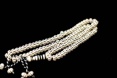 Müslümanların Allah 'a şükretmek için kullandığı 99 tespih ve siyah çizgili İslami tespih duası. Cümleleri kullanarak Allah' ı övmek ve övmek gibi. En büyük, en seçici odak noktası.