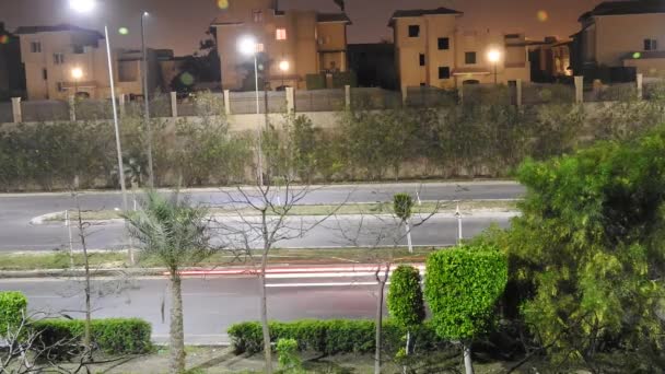 エジプト 2018年4月7日 緑豊かなエリアや木々に囲まれたギザの路上で夜の移動車両や車の時間経過 都市の通りや日常活動のトラフィックのトップビュー 選択的フォーカス — ストック動画