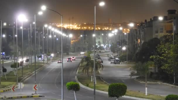 エジプト 2018年4月7日 緑豊かなエリアや木々に囲まれたギザの路上で夜の移動車両や車の時間経過 都市の通りや日常活動のトラフィックのトップビュー 選択的フォーカス — ストック動画