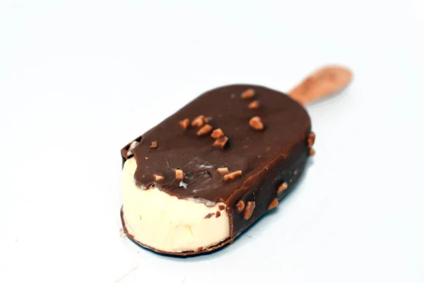 Rich vanilla flavored ice cream in cracking brown milk chocolate and roasted almond isolated on white background, Vanilla ice cream stick coated and covered with a layer of dark chocolate with nuts
