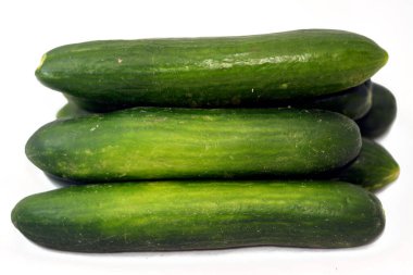 Beyaz arka planda izole edilmiş taze yeşil salatalık yığını taze çiğ organik salatalık seçici odak noktası sağlıklı gıda tarım vegan konsepti.