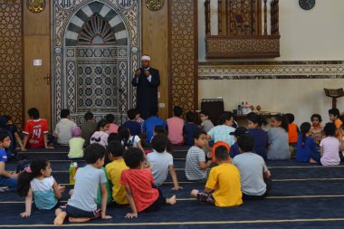 Kahire, Mısır, 31 Mayıs 2022: Cami vaizi İmam, camideki çocuklara yönelik yaz İslami eğitim programı sırasında camide genç Müslüman çocuklara vaaz veriyor.