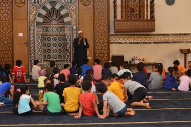 Kahire, Mısır, 31 Mayıs 2022: Cami vaizi İmam, camideki çocuklara yönelik yaz İslami eğitim programı sırasında camide genç Müslüman çocuklara vaaz veriyor.