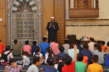 Kahire, Mısır, 31 Mayıs 2022: Cami vaizi İmam, camideki çocuklara yönelik yaz İslami eğitim programı sırasında camide genç Müslüman çocuklara vaaz veriyor.
