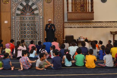 Kahire, Mısır, 31 Mayıs 2022: Cami vaizi İmam, camideki çocuklara yönelik yaz İslami eğitim programı sırasında camide genç Müslüman çocuklara vaaz veriyor.