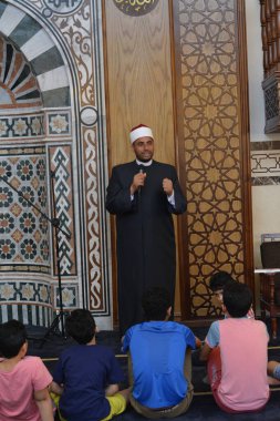 Kahire, Mısır, 31 Mayıs 2022: Cami vaizi İmam, camideki çocuklara yönelik yaz İslami eğitim programı sırasında camide genç Müslüman çocuklara vaaz veriyor.
