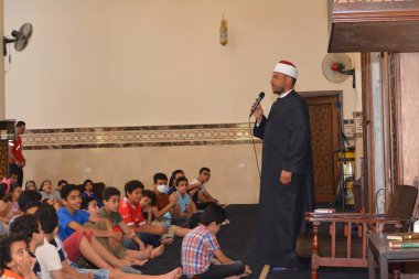 Kahire, Mısır, 31 Mayıs 2022: Cami vaizi İmam, camideki çocuklara yönelik yaz İslami eğitim programı sırasında camide genç Müslüman çocuklara vaaz veriyor.