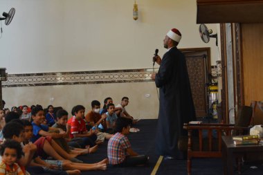 Kahire, Mısır, 31 Mayıs 2022: Cami vaizi İmam, camideki çocuklara yönelik yaz İslami eğitim programı sırasında camide genç Müslüman çocuklara vaaz veriyor.