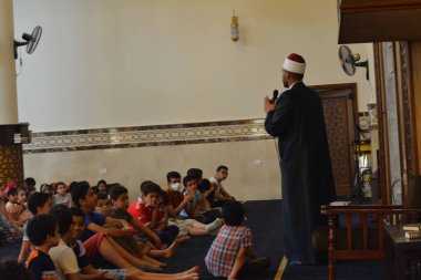 Kahire, Mısır, 31 Mayıs 2022: Cami vaizi İmam, camideki çocuklara yönelik yaz İslami eğitim programı sırasında camide genç Müslüman çocuklara vaaz veriyor.
