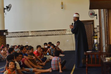 Kahire, Mısır, 31 Mayıs 2022: Cami vaizi İmam, camideki çocuklara yönelik yaz İslami eğitim programı sırasında camide genç Müslüman çocuklara vaaz veriyor.