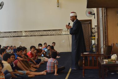 Kahire, Mısır, 31 Mayıs 2022: Cami vaizi İmam, camideki çocuklara yönelik yaz İslami eğitim programı sırasında camide genç Müslüman çocuklara vaaz veriyor.