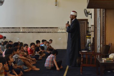 Kahire, Mısır, 31 Mayıs 2022: Cami vaizi İmam, camideki çocuklara yönelik yaz İslami eğitim programı sırasında camide genç Müslüman çocuklara vaaz veriyor.
