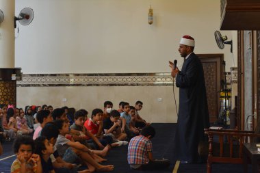Kahire, Mısır, 31 Mayıs 2022: Cami vaizi İmam, camideki çocuklara yönelik yaz İslami eğitim programı sırasında camide genç Müslüman çocuklara vaaz veriyor.