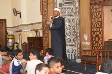 Kahire, Mısır, 31 Mayıs 2022: Cami vaizi İmam, camideki çocuklara yönelik yaz İslami eğitim programı sırasında camide genç Müslüman çocuklara vaaz veriyor.