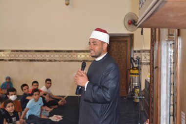 Kahire, Mısır, 31 Mayıs 2022: Cami vaizi İmam, camideki çocuklara yönelik yaz İslami eğitim programı sırasında camide genç Müslüman çocuklara vaaz veriyor.